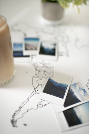 Foto de Polaroid Photos on Travel World Map with Iced Coffee and Plant - Imagen libre de derechos