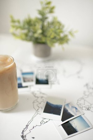 Téléchargez les photos : Photos Polaroid sur la carte du monde de voyage avec café glacé et plante - en image libre de droit