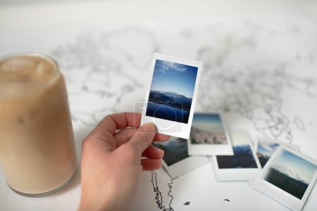 Foto de Foto de la Polaroid de la montaña de mano en el mapa del mundo con café helado - Imagen libre de derechos