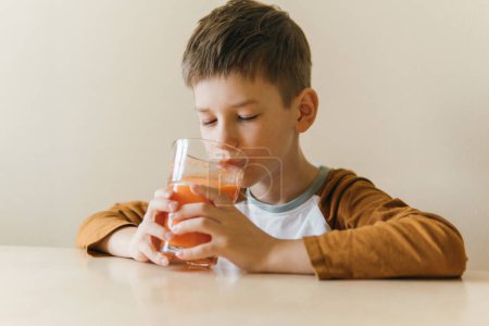 Foto de Boy sitting at the table and drinking orange juice - Imagen libre de derechos