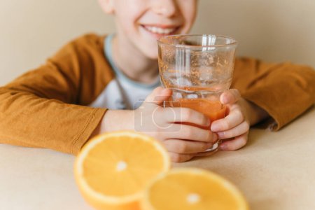 Photo for A glass of orange juice in the hands of a boy - Royalty Free Image