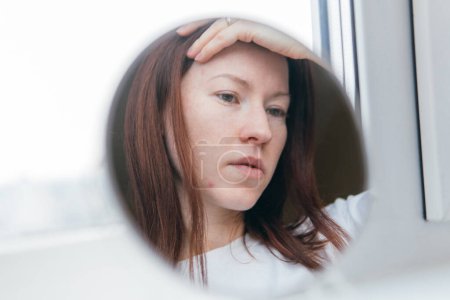 Foto de White woman with acne looks in the mirror - Imagen libre de derechos