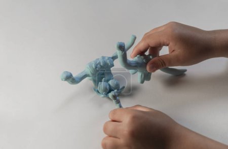 Foto de Niño jugando con figuritas de dinosaurios de plastilina. - Imagen libre de derechos