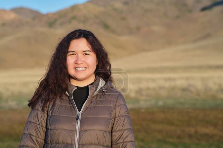Téléchargez les photos : Portrait d'une femme asiatique souriante debout contre les collines - en image libre de droit