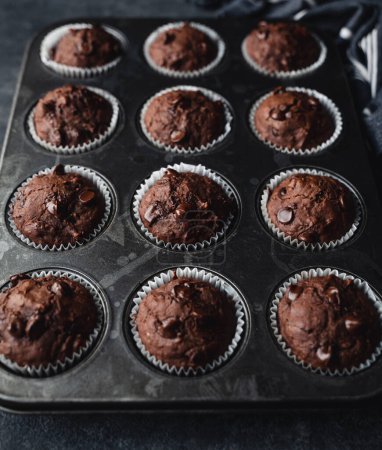 Téléchargez les photos : Close up of tin of chocolate zucchini muffins on black background. - en image libre de droit