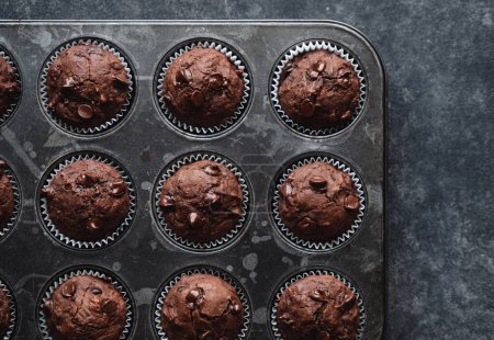 Photo for Overhead of tin of chocolate zucchini muffins on black background. - Royalty Free Image