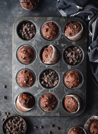 Foto de Overhead of tin of chocolate zucchini muffins on black background. - Imagen libre de derechos