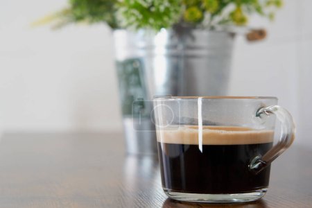 Téléchargez les photos : Delicious cup of black coffee with foam on a wooden table - en image libre de droit