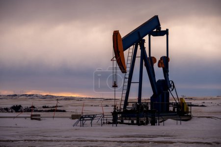 Photo for Pump jacks drawing crude oil from deep under ground on a moody Alberta morning in winter. - Royalty Free Image