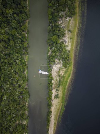 Photo for Beautiful aerial top down drone view to large rivers, white tour boat and green rainforest in the Brazilian Amazon - Royalty Free Image