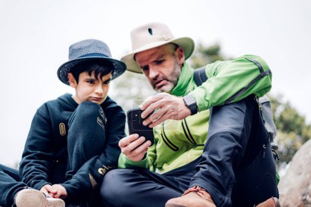 Photo for Father and son spending an autumn day in the mountains, using th - Royalty Free Image