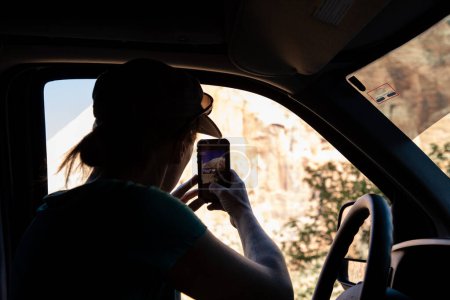 Photo for Young woman taking photo with phone out of van in Zion National Park - Royalty Free Image