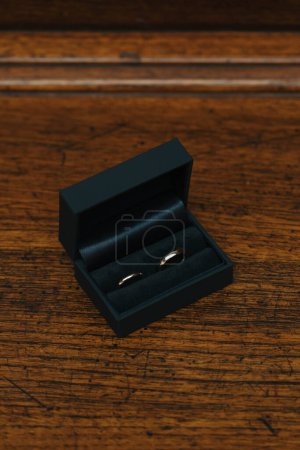 Téléchargez les photos : Anneaux de mariage dorés dans leur boîte noire sur une table en bois - en image libre de droit