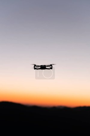 Drohne fliegt bei Sonnenaufgang mit Bergen im Hintergrund