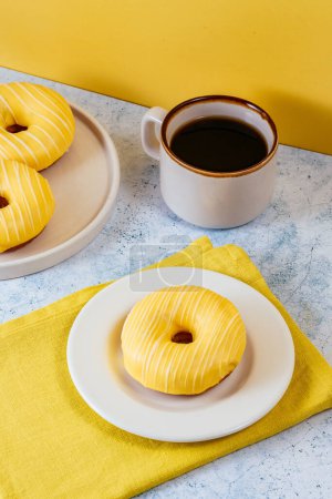 Photo for Lemon doughnuts in yellow glaze, coffee in a glass. - Royalty Free Image