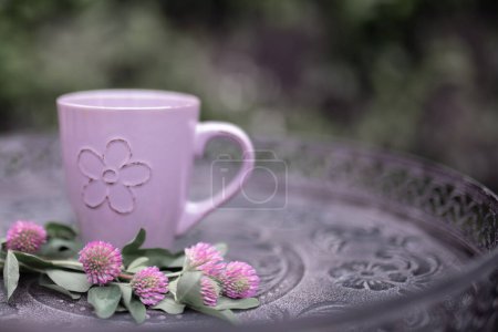 Foto de Lilac coffee cup and colorful lilac flowers on garden table - Imagen libre de derechos