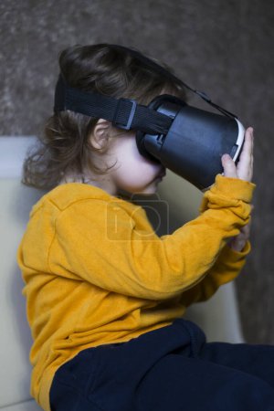 Téléchargez les photos : Petite fille jouer à des jeux virtuels dans des lunettes vr et les toucher - en image libre de droit
