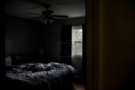 Téléchargez les photos : Lit gris désordonné non fait dans une petite chambre à coucher en après-midi - en image libre de droit
