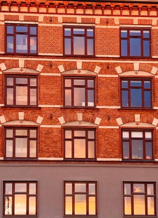 Téléchargez les photos : Coucher de soleil reflété dans les fenêtres d'un bâtiment en copenhagen - en image libre de droit