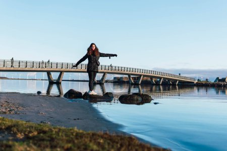 Foto de Mujer al lado de un río tiene un puente en el fondo - Imagen libre de derechos