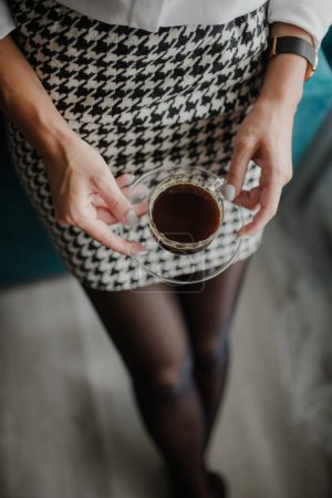 Téléchargez les photos : Woman in work outfit holding a cup of freshly made coffee. - en image libre de droit