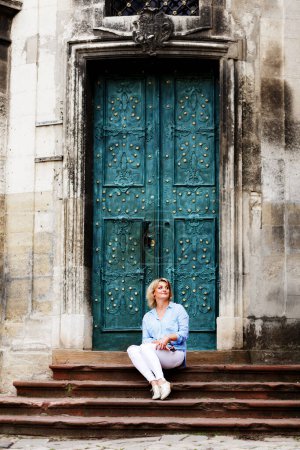 Foto de Woman sits against the background of a luxurious medieval building - Imagen libre de derechos