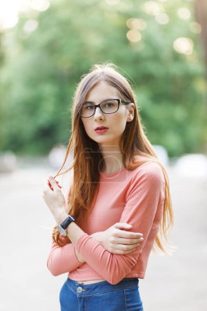 Téléchargez les photos : Jeune femme aux cheveux bruns en lunettes et un pull dans un parc de printemps - en image libre de droit