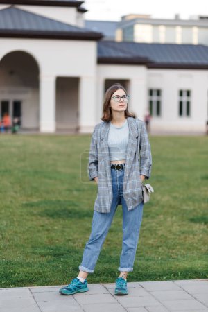 Foto de Young female student in a jacket and jeans on campus - Imagen libre de derechos