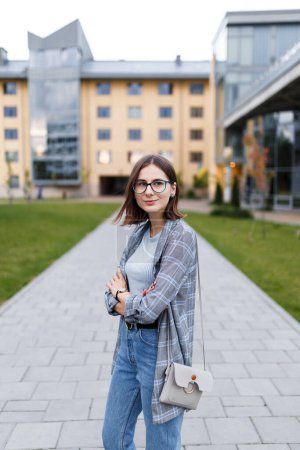 Photo for Young female student in a jacket and jeans on campus - Royalty Free Image