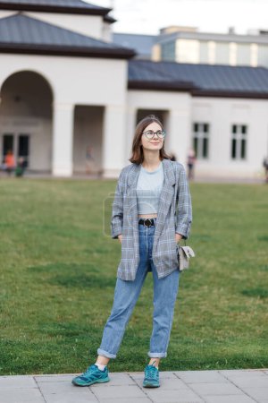 Téléchargez les photos : Young female student in a jacket and jeans on campus - en image libre de droit