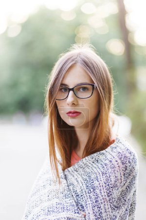 Téléchargez les photos : Jeune femme aux cheveux bruns en lunettes et un pull dans un parc de printemps - en image libre de droit