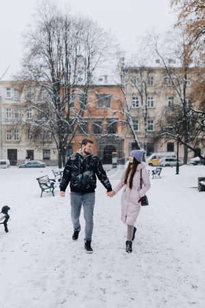 Photo for Couple in love is walking through a snowy winter town - Royalty Free Image