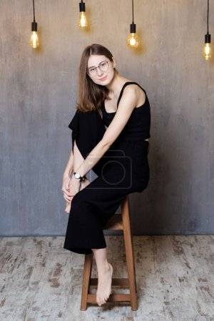 Téléchargez les photos : A young confident happy woman sitting on a chair in the studio - en image libre de droit