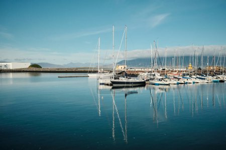 Téléchargez les photos : Picturesque scenery of sailboats moored on pier floating in rippling calm sea water on sunny day in Reykjavik - en image libre de droit
