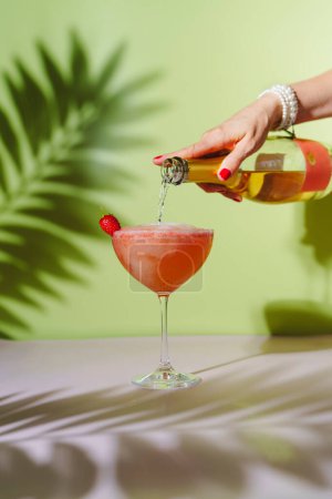Téléchargez les photos : La main d'une femme verse du champagne dans un verre à cocktail. - en image libre de droit