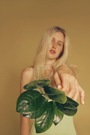 Téléchargez les photos : Blonde freckles woman and natural make-up holding leaves - en image libre de droit