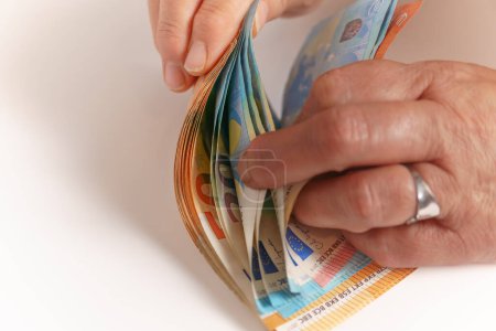Téléchargez les photos : Femme comptant de l'argent sur une table blanche - en image libre de droit