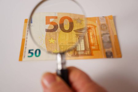 Téléchargez les photos : Fifty euro banknote viewed with a magnifying glass - en image libre de droit