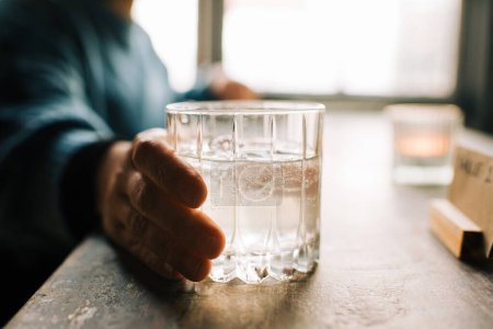 Téléchargez les photos : Person holding a glass of fizzy water on a table - en image libre de droit