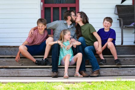 Photo for Happy family of five sitting on farmhouse steps. - Royalty Free Image