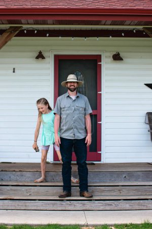 Photo for Father and daughter on farmhouse steps. - Royalty Free Image