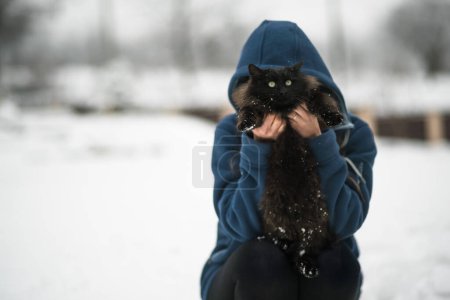 Foto de Chica sosteniendo gato negro en la nieve - Imagen libre de derechos