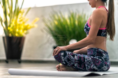 Téléchargez les photos : Jeune femme latine méditant assis sur un tapis de yoga - en image libre de droit