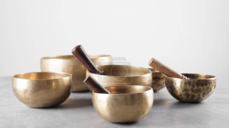 Photo for Group of tibetan singing bowls with sticks on grey stone table - Royalty Free Image