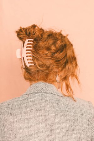 Téléchargez les photos : Une femme d'affaires dans un blazer avec une pince à cheveux contre un dos rose - en image libre de droit