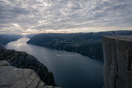 Photo for A Hiker Standing At The Edge Of A Cliff, Preikestolen, Stavanger - Royalty Free Image