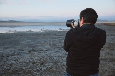 Foto de Hombre fotógrafo de la naturaleza con una cámara dispara un paisaje - Imagen libre de derechos