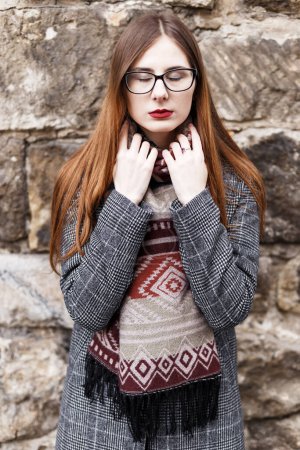 Téléchargez les photos : Jeune femme en lunettes portant un manteau enveloppé dans une écharpe - en image libre de droit