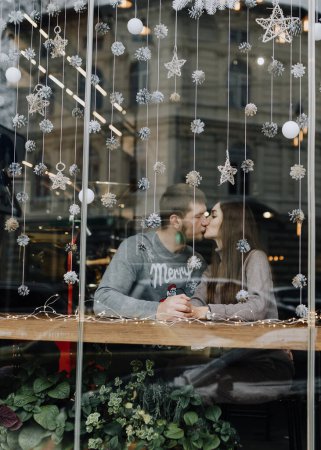 Photo for Couple in love kissing on a date in a cafe in winter - Royalty Free Image