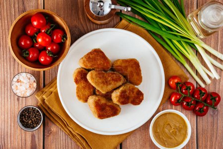 Foto de Fried chicken nuggets in the shape of a heart on a plate, mustard sauce next to it - Imagen libre de derechos